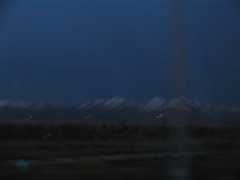 1995 Ford C-350 (Centurion Conversions) - A blurry view of mountains at dusk, with faint lights visible in the distance.