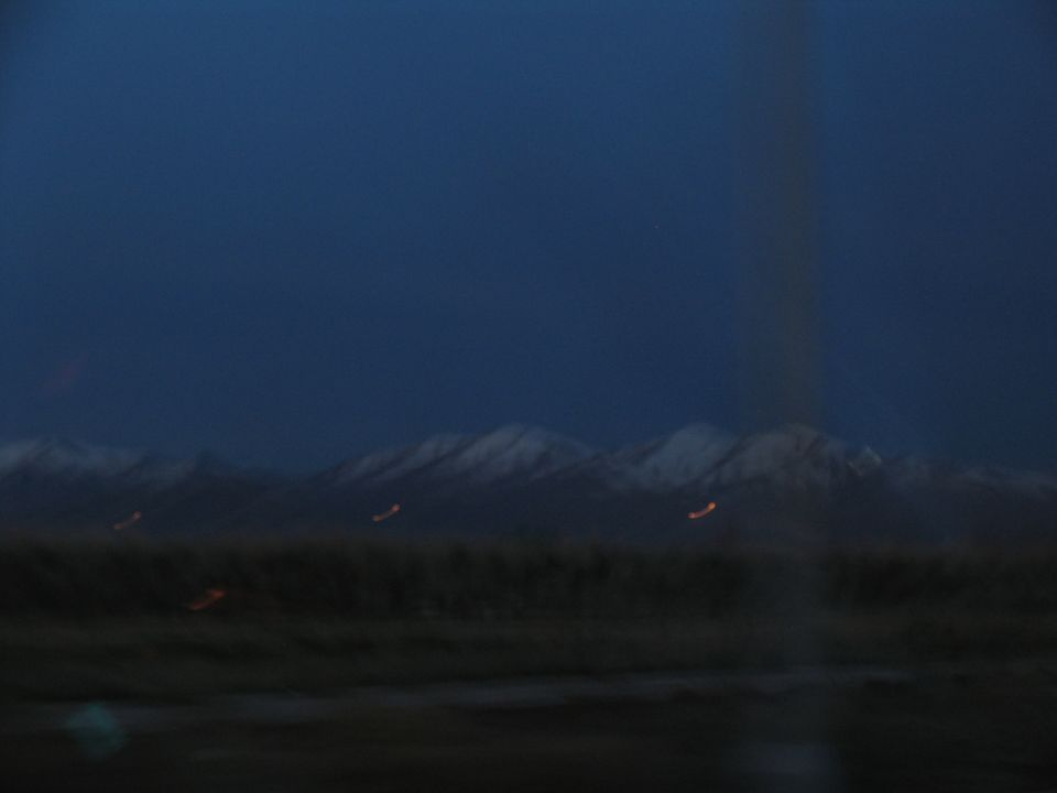Dark landscape with snow-capped mountains under a deep blue sky