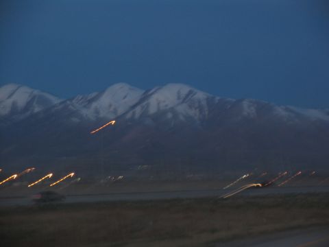 1995 Ford C-350 (Centurion Conversions) - Streaking lights blur across the landscape with mountains in the background at dusk.