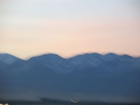 1995 Ford C-350 (Centurion Conversions) - A blurry mountain range is visible against a soft pink and white sky during twilight.