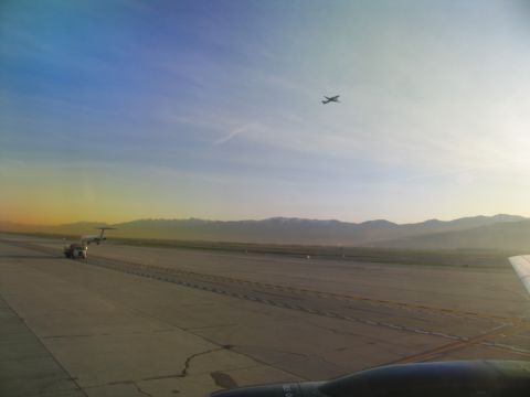 1995 Ford C-350 (Centurion Conversions) - An airport scene at sunrise with mountains on the horizon and an airplane in the sky.