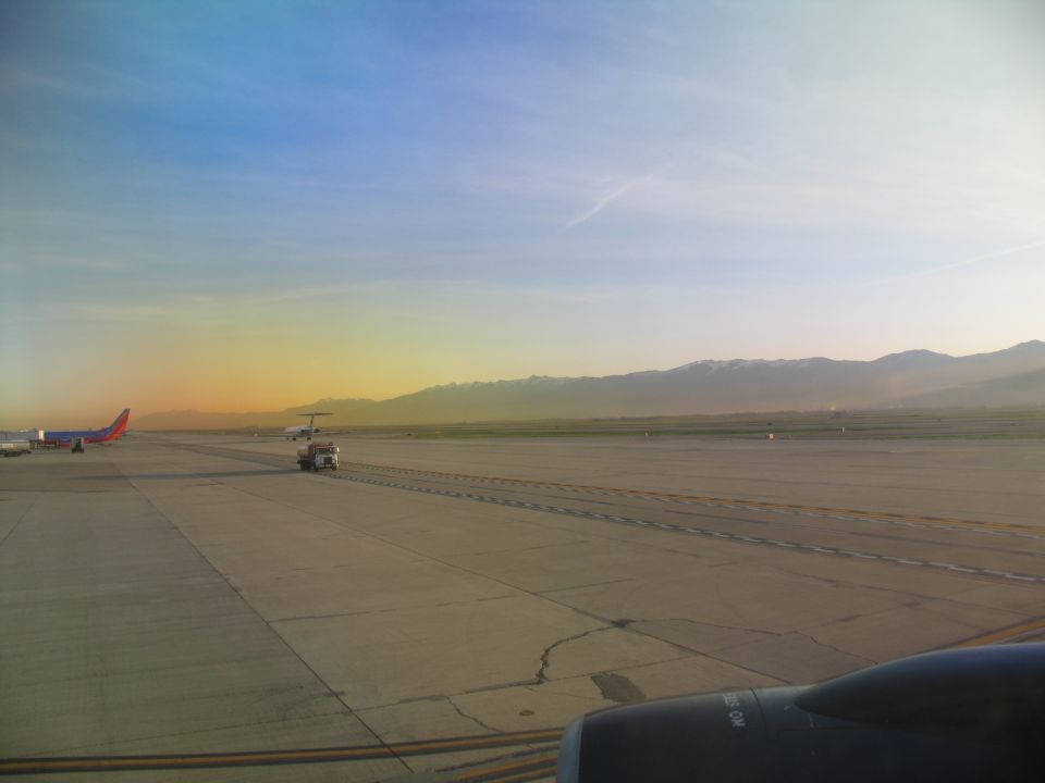 Airport tarmac at sunrise with airplanes and mountains in distance
