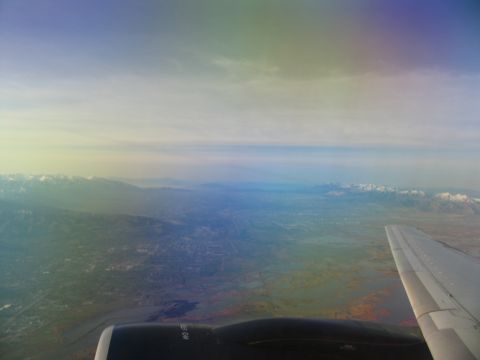 1995 Ford C-350 (Centurion Conversions) - View from an airplane window shows a wing and engine against a backdrop of a valley and distant mountains.