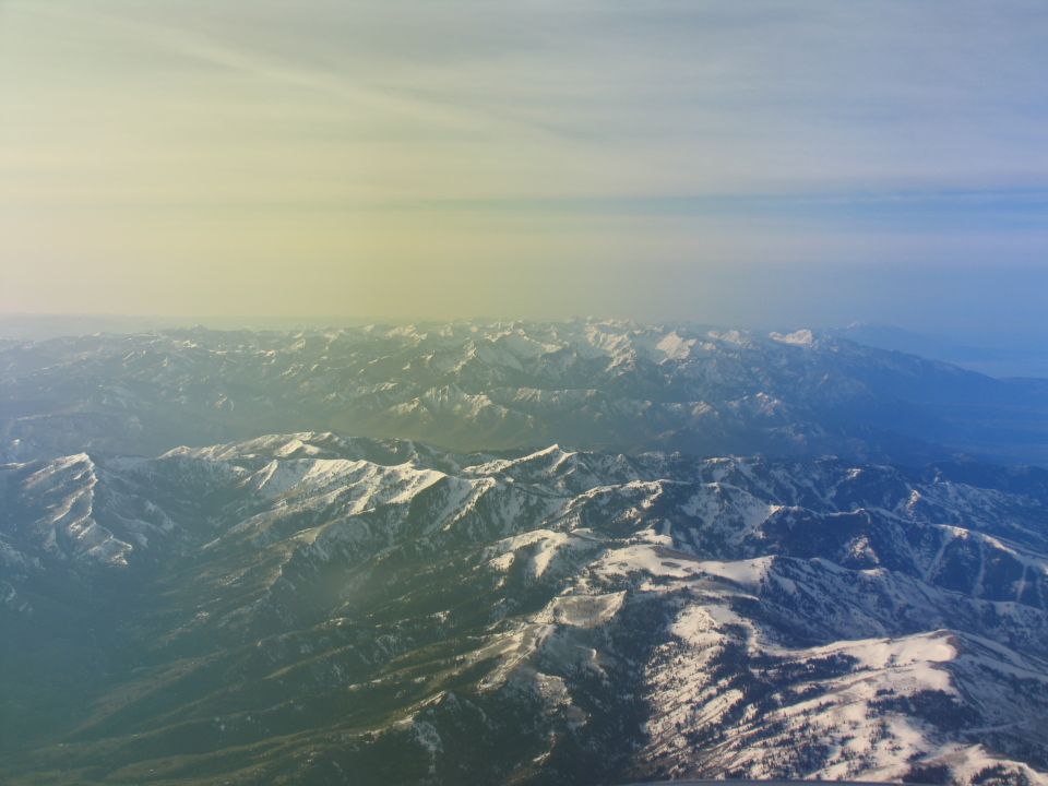 Aerial view of snow-covered mountain ranges under a hazy sky