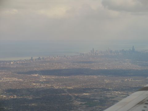 1995 Ford C-350 (Centurion Conversions) - An aerial view captures a city skyline along a coastline, with clouds overhead.