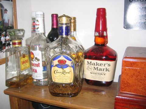 1979 Ford Bronco - A shelf displays various bottles of spirits, including tequila, vodka, and whiskey, alongside a framed photograph.