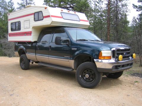 1999 Ford F-250 - A 1999 Ford F-250 truck is equipped with a camper shell and parked outdoors.