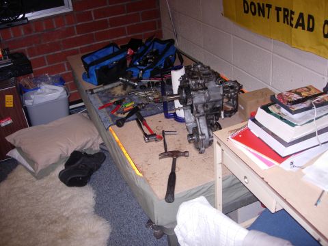 1985 Toyota Hilux - A disassembled engine and transmission sit on a table, surrounded by tools and other items.