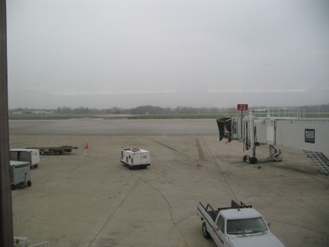 1995 Ford C-350 (Centurion Conversions) - An airport tarmac scene shows a white pickup truck, a jet bridge, and various service vehicles under an overcast sky.
