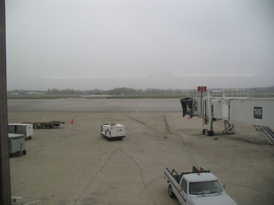 White pickup truck parked at airport gate 22 with jet bridge and service vehicles