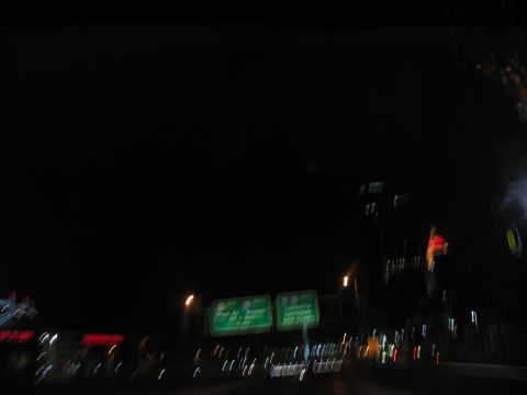 1995 Ford C-350 (Centurion Conversions) - Driving at night on a highway with illuminated signs and city lights in the distance.