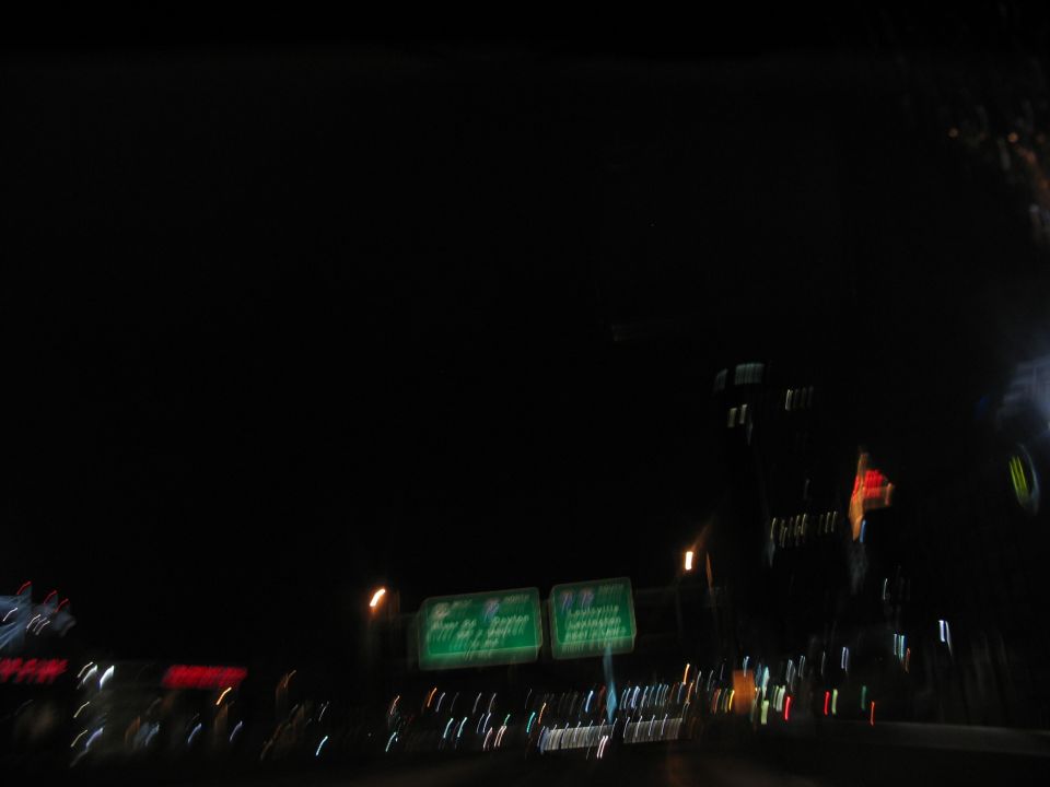 Nighttime highway scene with green directional signs and blurred lights