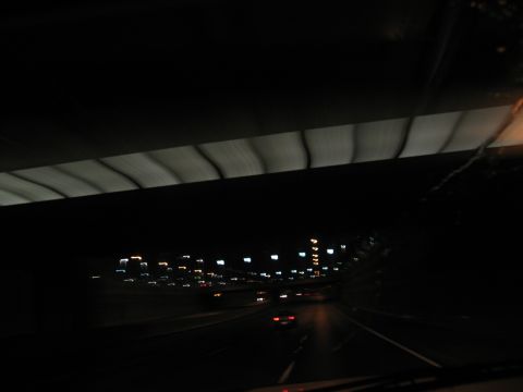 1995 Ford C-350 (Centurion Conversions) - A blurry view of a highway at night, with lights from distant buildings and vehicles.