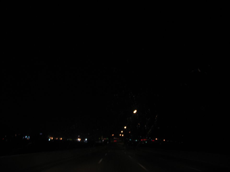 Driving on a highway at night with distant city lights