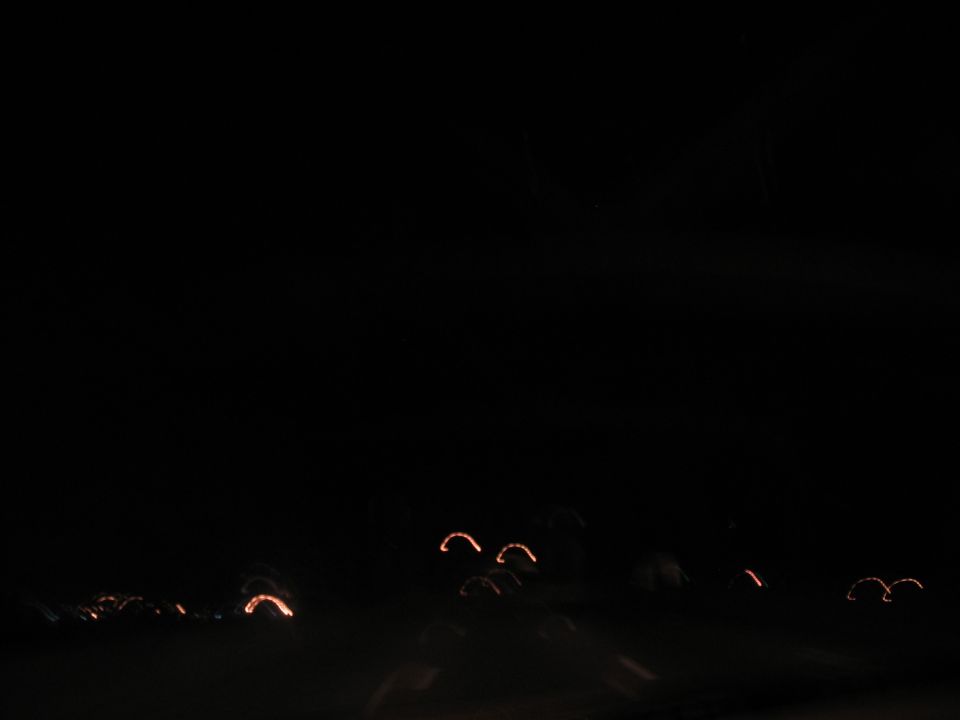 Abstract streaks of orange light against a black background, possibly from car taillights at night