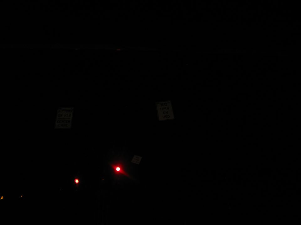 Two signs and red lights in a dark scene