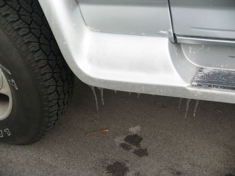 1995 Ford C-350 (Centurion Conversions) - Icicles hang from the side panel of a vehicle near the tire.