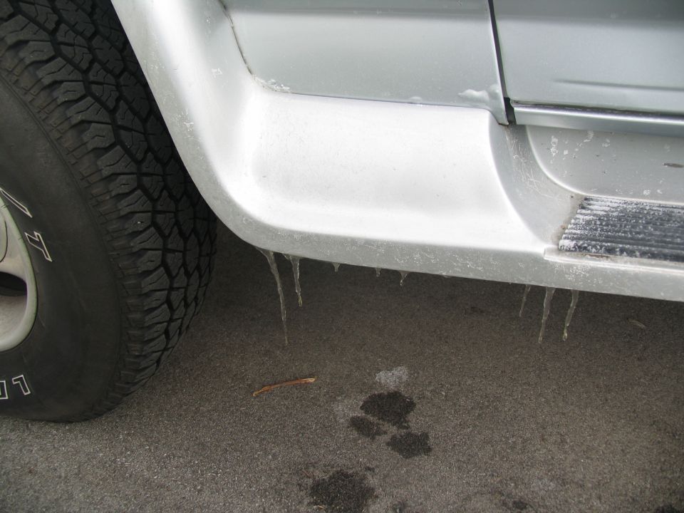 Side panel and tire of a vehicle with icicles hanging from the lower edge