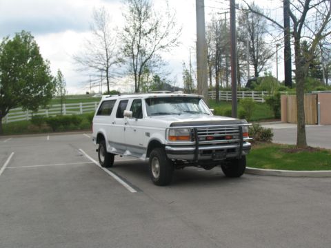 1995 Ford C-350 (Centurion Conversions) - A white Ford SUV is parked in a lot on a cloudy day.