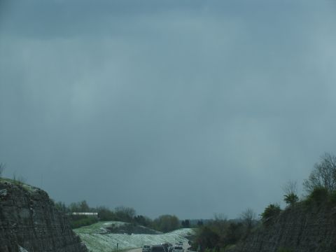 1995 Ford C-350 (Centurion Conversions) - Vehicles travel along a highway bordered by rocky cuts and green hills under a heavy, overcast sky.