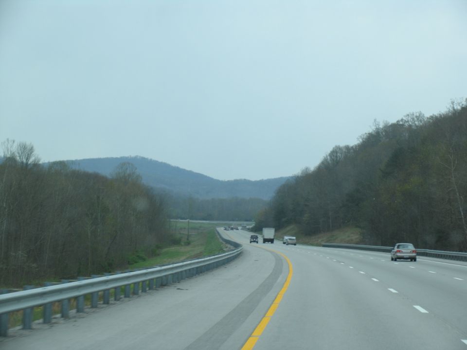 Cars and trucks on a highway with hills in the background