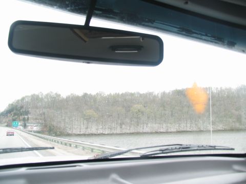 1995 Ford C-350 (Centurion Conversions) - View from inside a vehicle on a highway with a lake and trees visible.