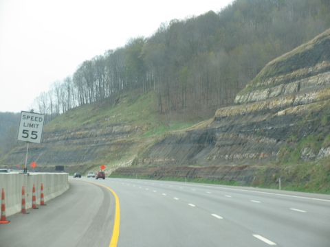 1995 Ford C-350 (Centurion Conversions) - Driving on a highway with a speed limit sign and a view of layered rock formations on a hillside.