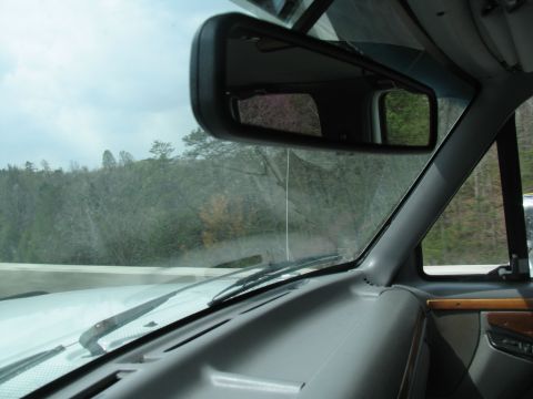 1995 Ford C-350 (Centurion Conversions) - Driving through a wooded area with a cloudy sky overhead.