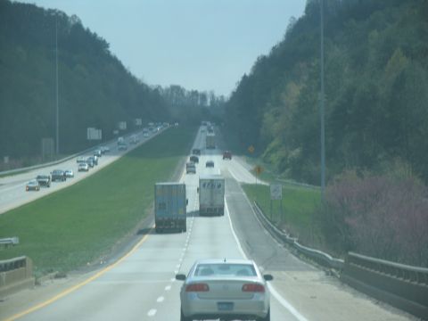 1995 Ford C-350 (Centurion Conversions) - Vehicles travel on a multi-lane highway surrounded by hills and trees.