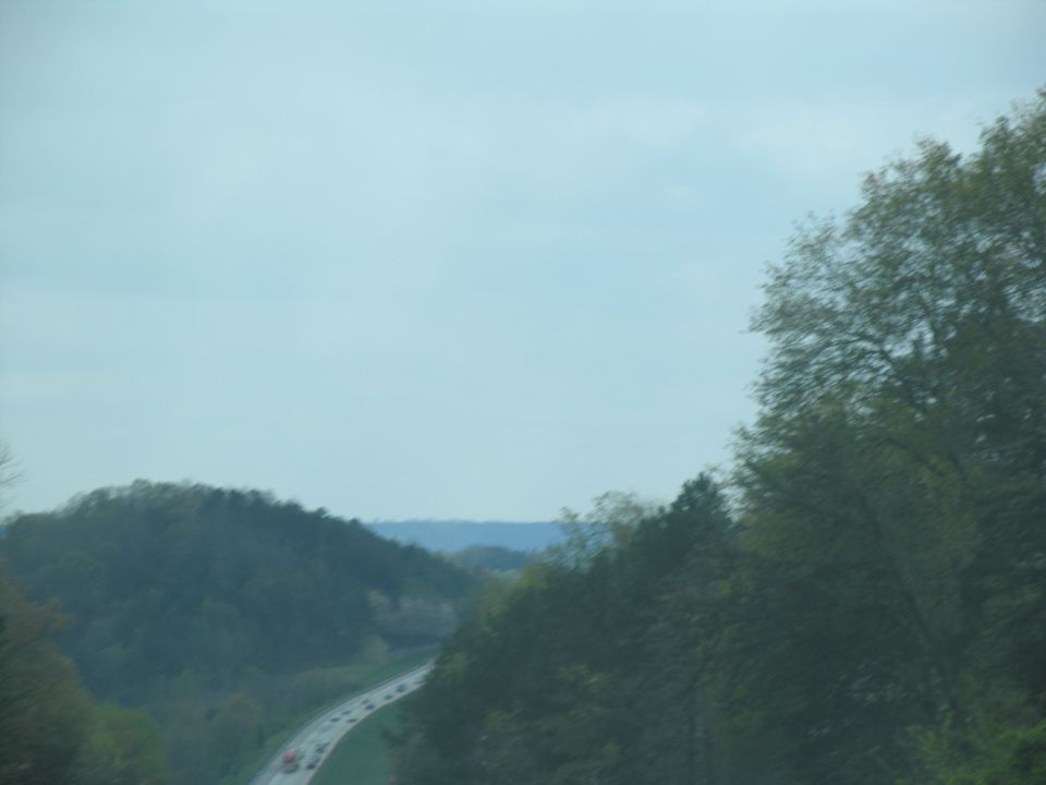 Highway winding through hills with trees and cars on the road