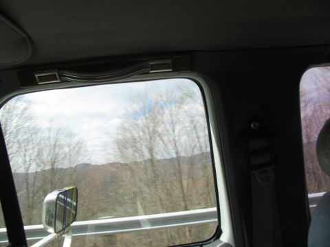 1995 Ford C-350 (Centurion Conversions) - View from the passenger seat of a vehicle, looking out at a landscape of bare trees and distant hills.