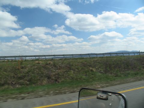 1995 Ford C-350 (Centurion Conversions) - View from a vehicle traveling on a highway under a cloudy blue sky.