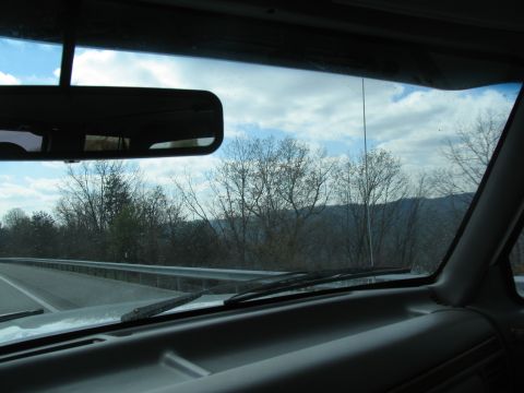 1995 Ford C-350 (Centurion Conversions) - View from inside a vehicle traveling on a highway, showing the dashboard, windshield, and the passing scenery.