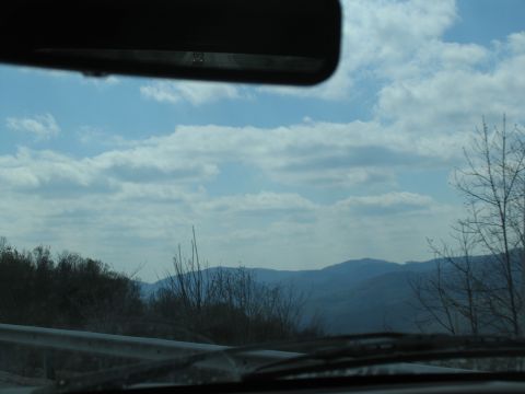 1995 Ford C-350 (Centurion Conversions) - View from inside a vehicle traveling through a mountainous region on a cloudy day.
