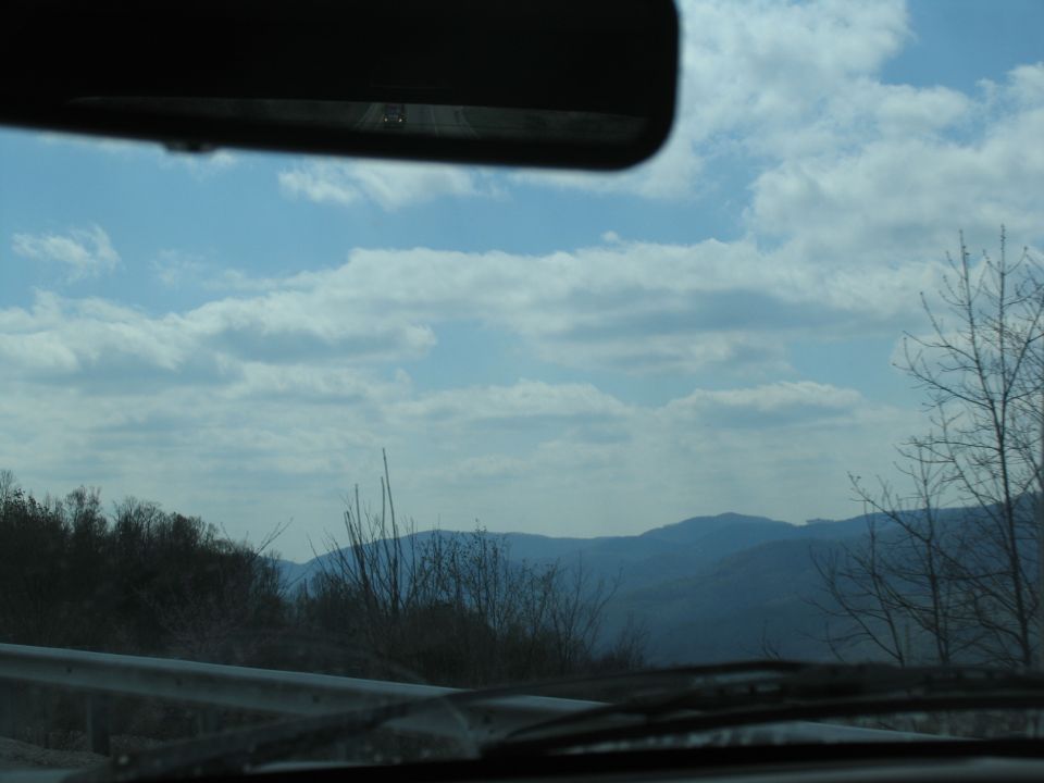Interior view from a vehicle looking out at mountains under a cloudy sky