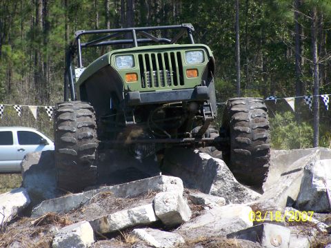 1989 Ford Bronco - A modified off-road vehicle tackles a challenging obstacle course with large tires and a reinforced roll cage.