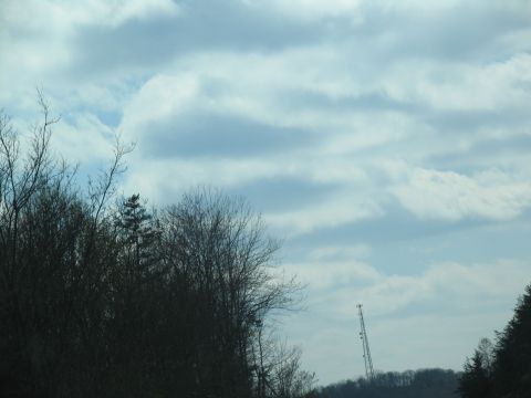 1995 Ford C-350 (Centurion Conversions) - A distant cell tower stands on a hill, silhouetted against a cloudy sky.