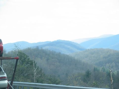 1995 Ford C-350 (Centurion Conversions) - A red vehicle part is visible on a trailer in front of a hazy mountain range.