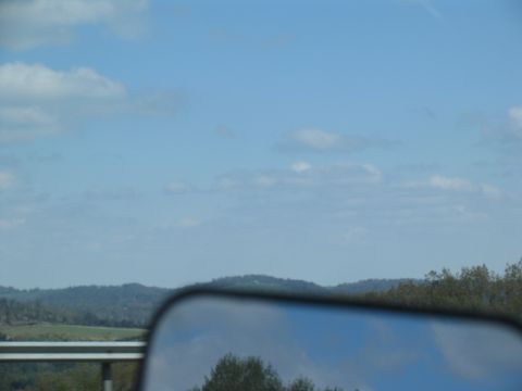 1995 Ford C-350 (Centurion Conversions) - Reflection in the side mirror shows trees and the sky on a cloudy day.