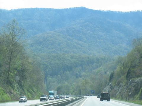 1995 Ford C-350 (Centurion Conversions) - A highway passes through a valley with tree-covered mountains under a hazy sky.