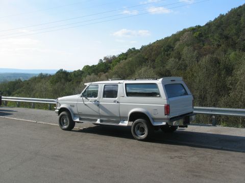1995 Ford C-350 (Centurion Conversions) - This extended cab pickup truck features a camper shell, giving it a unique, elongated profile against a scenic backdrop.
