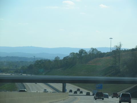 1995 Ford C-350 (Centurion Conversions) - A highway scene with multiple vehicles driving under an overpass on a clear day.