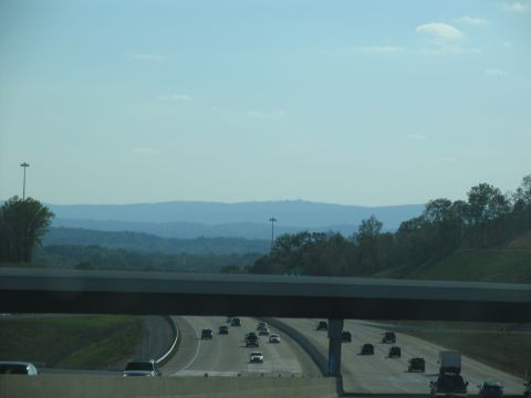 1995 Ford C-350 (Centurion Conversions) - Vehicles travel along a multi-lane highway with rolling hills and distant mountains visible under a clear blue sky.
