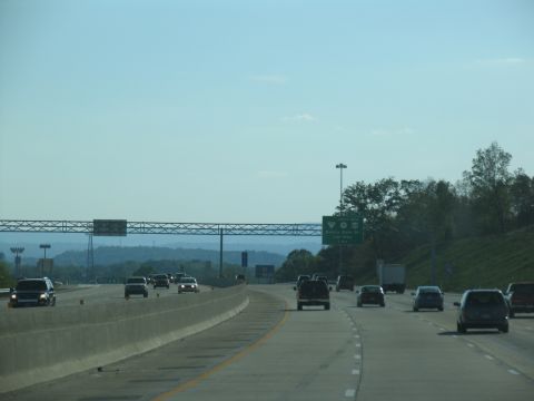1995 Ford C-350 (Centurion Conversions) - Traffic moves along a multi-lane highway with overhead signs and trees lining the roadside.