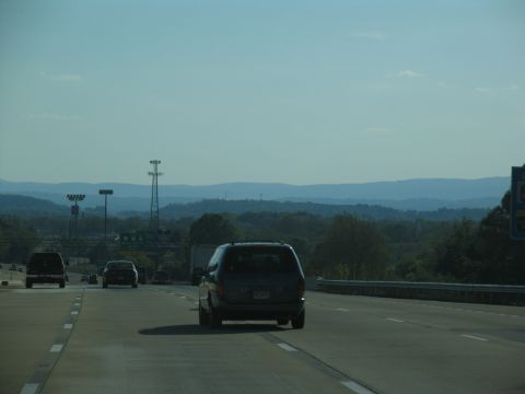 1995 Ford C-350 (Centurion Conversions) - Driving on a highway with multiple vehicles and a scenic view of rolling hills in the distance.