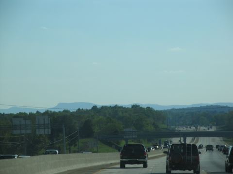 1995 Ford C-350 (Centurion Conversions) - Vehicles travel along a highway under a clear blue sky with distant mountains.