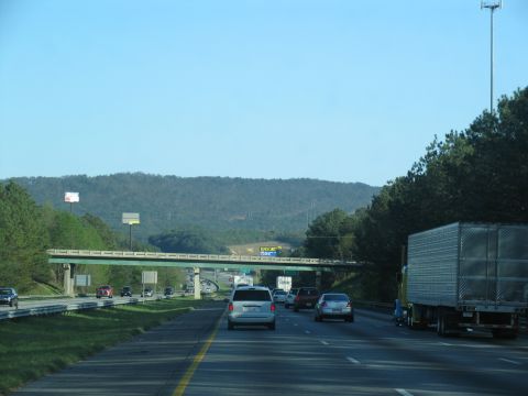 1995 Ford C-350 (Centurion Conversions) - A view from a vehicle traveling on a highway, showing other cars, trucks, and an overpass in the distance.
