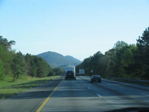 1995 Ford C-350 (Centurion Conversions) - Driving on a highway with mountains in the background and other vehicles on the road.
