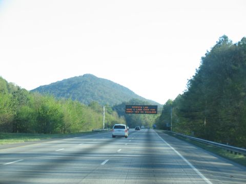 1995 Ford C-350 (Centurion Conversions) - A white van drives on a highway under a digital sign.