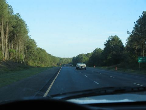 1995 Ford C-350 (Centurion Conversions) - Driving on a highway with a white convertible ahead and trees lining the road.